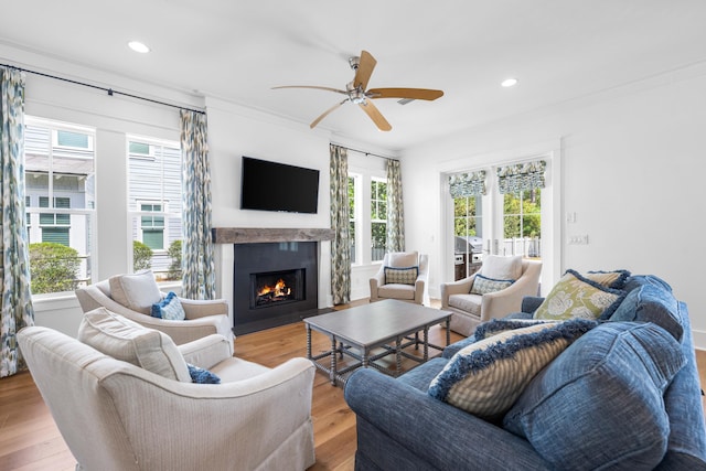 living room featuring a wealth of natural light, ceiling fan, crown molding, and light wood-type flooring