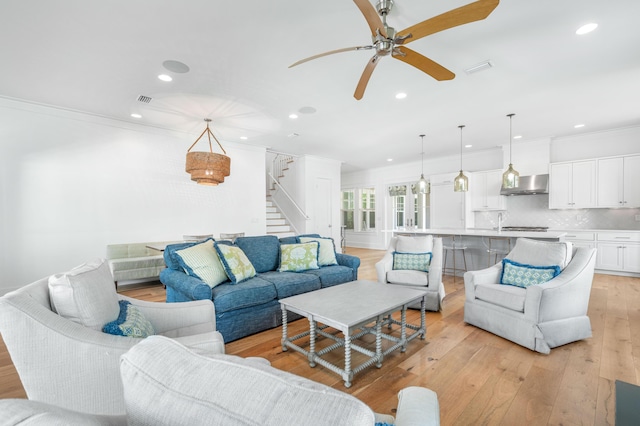 living room featuring ceiling fan, sink, light hardwood / wood-style floors, and ornamental molding