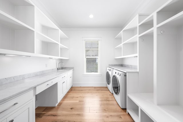 laundry room featuring washer and dryer, light hardwood / wood-style flooring, and sink