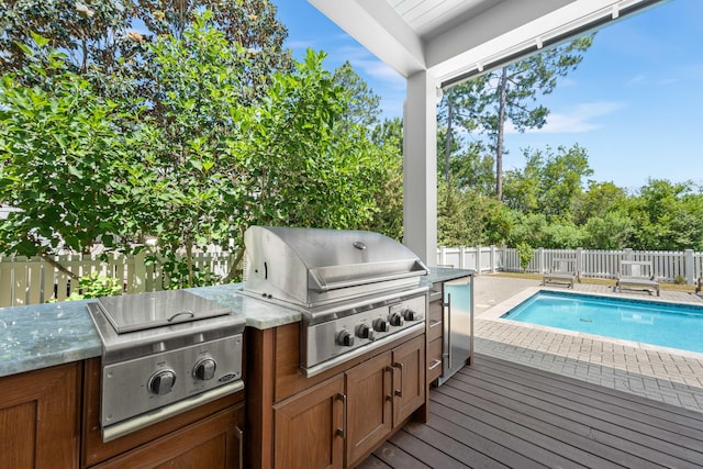 view of pool featuring an outdoor kitchen, a grill, and a deck