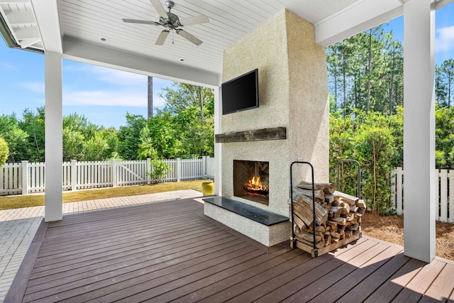 deck with ceiling fan and exterior fireplace