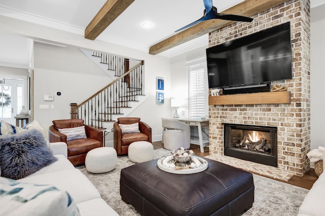 living room featuring beamed ceiling, a wealth of natural light, a fireplace, and ceiling fan