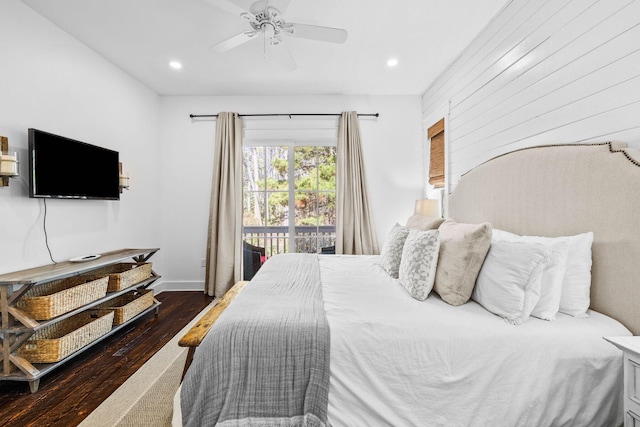 bedroom with access to exterior, ceiling fan, dark hardwood / wood-style flooring, and wooden walls