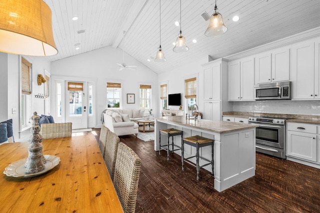 kitchen featuring a center island with sink, white cabinets, a breakfast bar area, ceiling fan, and stainless steel appliances