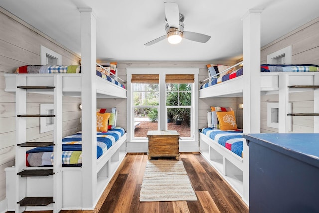 bedroom featuring ceiling fan, dark wood-type flooring, wood walls, and ornamental molding