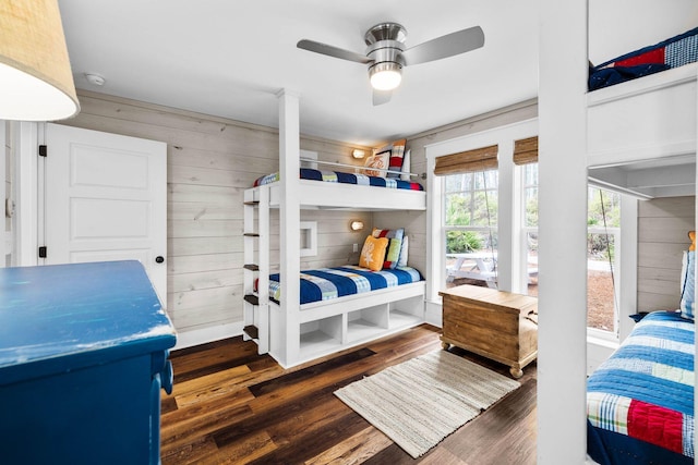 bedroom featuring dark hardwood / wood-style floors, ceiling fan, and wood walls