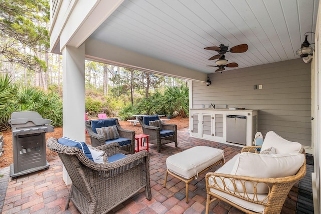 view of patio with area for grilling, ceiling fan, outdoor lounge area, and an outdoor kitchen