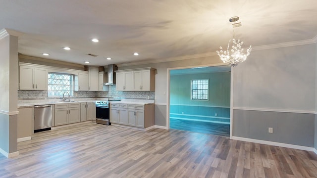 kitchen with stainless steel appliances, light wood-type flooring, pendant lighting, wall chimney exhaust hood, and sink