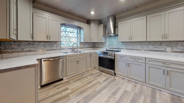 kitchen with appliances with stainless steel finishes, light stone counters, wall chimney exhaust hood, sink, and backsplash