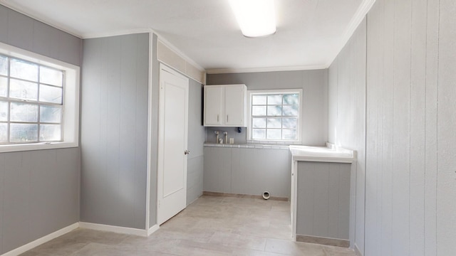 laundry area with ornamental molding, plenty of natural light, and cabinets