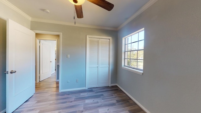 unfurnished bedroom with a closet, ceiling fan, crown molding, and light hardwood / wood-style flooring