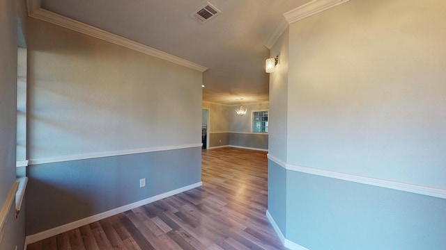 spare room featuring hardwood / wood-style floors, a chandelier, and ornamental molding