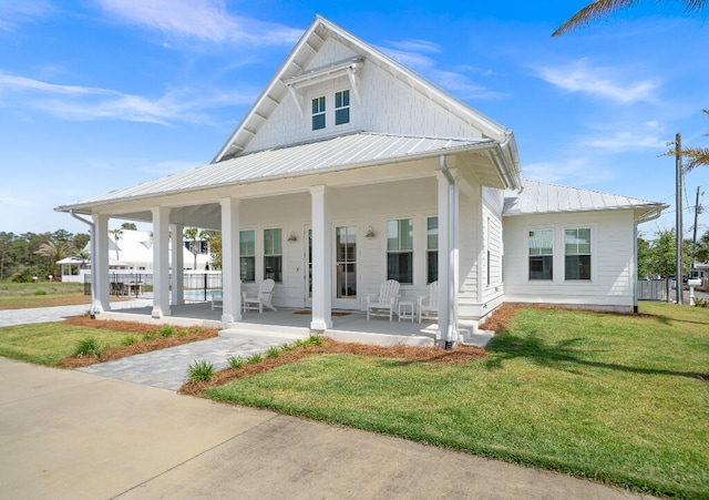 view of front of property with covered porch, a front lawn, and metal roof