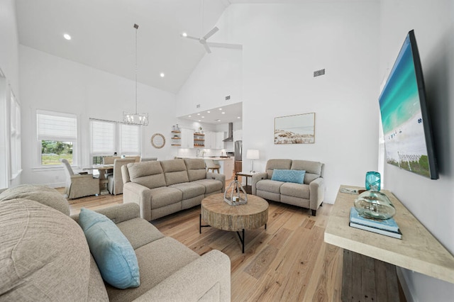 living area featuring high vaulted ceiling, a chandelier, light wood-type flooring, and recessed lighting