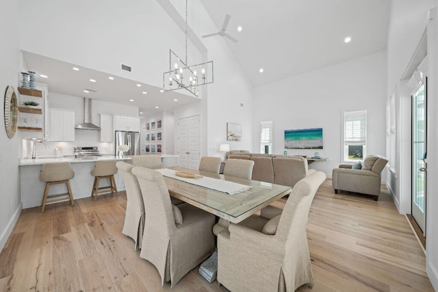 dining room featuring high vaulted ceiling, recessed lighting, light wood finished floors, ceiling fan, and a chandelier