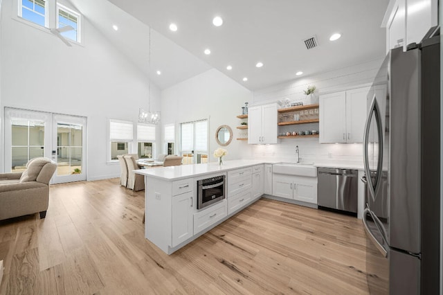 kitchen with appliances with stainless steel finishes, a sink, open shelves, high vaulted ceiling, and open floor plan