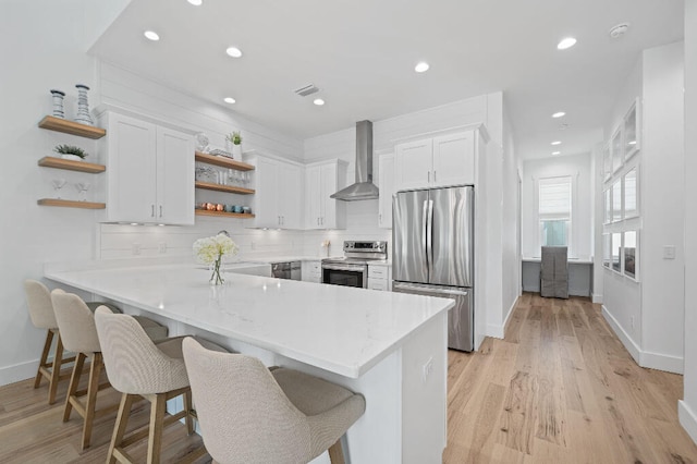 kitchen with stainless steel appliances, open shelves, wall chimney range hood, a peninsula, and white cabinetry