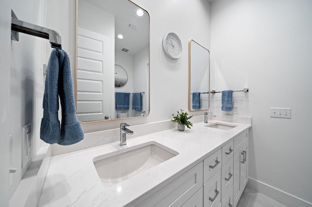 full bath featuring double vanity and baseboards