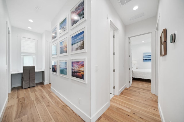 corridor featuring light wood-style flooring, a desk, recessed lighting, and baseboards