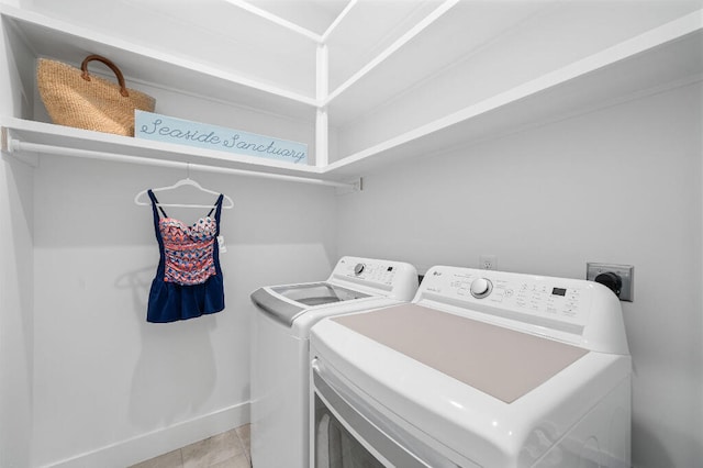 washroom featuring washing machine and dryer, light tile patterned floors, and baseboards