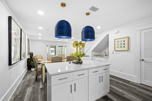 kitchen with pendant lighting, light stone counters, dark hardwood / wood-style flooring, and white cabinets