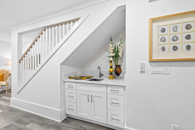 bar with white cabinetry, sink, and hardwood / wood-style floors