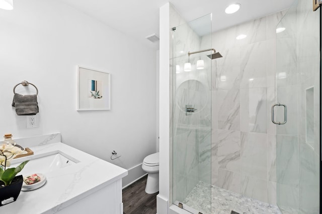 bathroom featuring vanity, wood-type flooring, a shower with door, and toilet