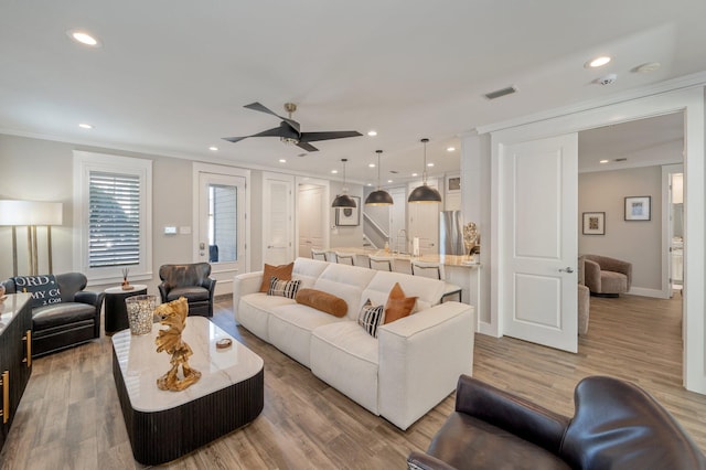 living room with hardwood / wood-style floors, ceiling fan, and ornamental molding