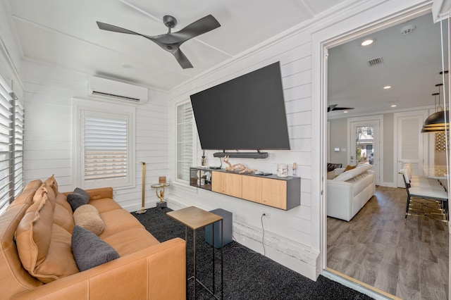 living room with hardwood / wood-style flooring, ceiling fan, wood walls, and an AC wall unit