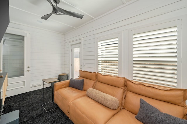 living room with carpet floors, ceiling fan, and wood walls