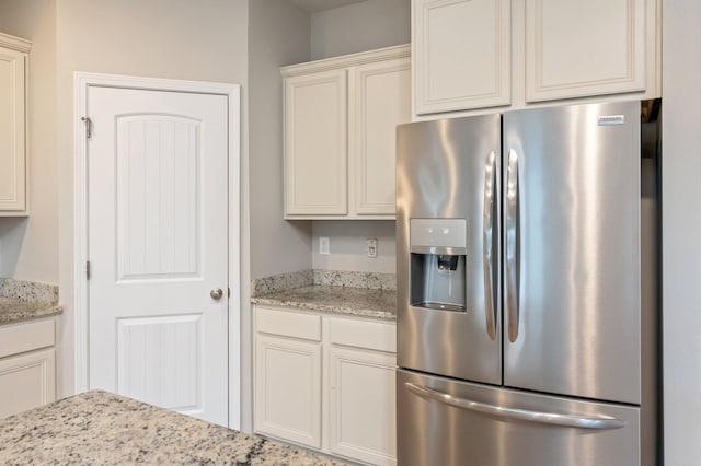 kitchen with stainless steel fridge with ice dispenser and light stone countertops