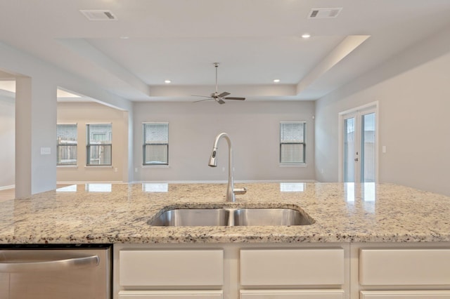 kitchen featuring sink, dishwasher, and light stone counters