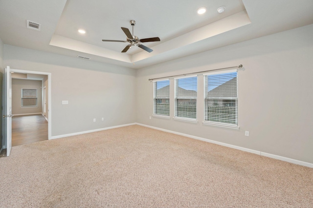 empty room with ceiling fan, a raised ceiling, and carpet