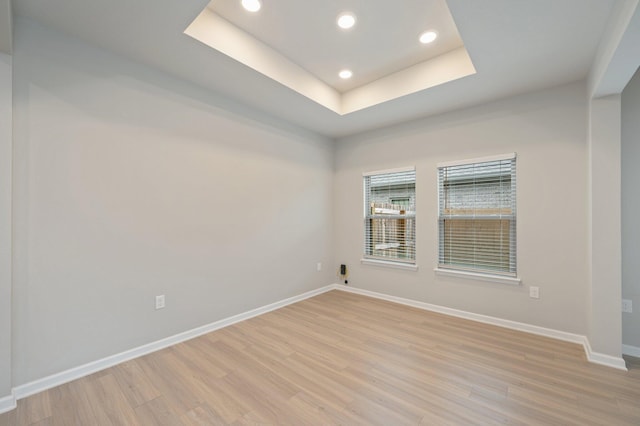 unfurnished room with a tray ceiling and light hardwood / wood-style floors