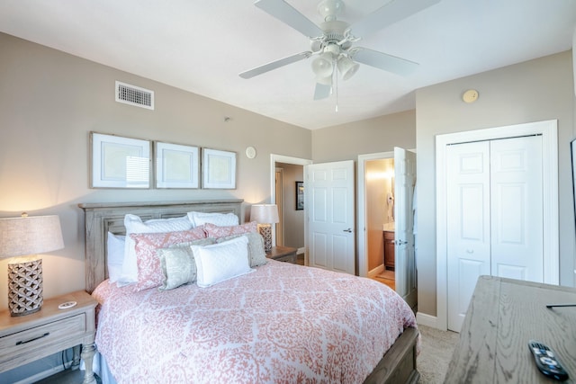 bedroom featuring ceiling fan, ensuite bathroom, a closet, and light colored carpet