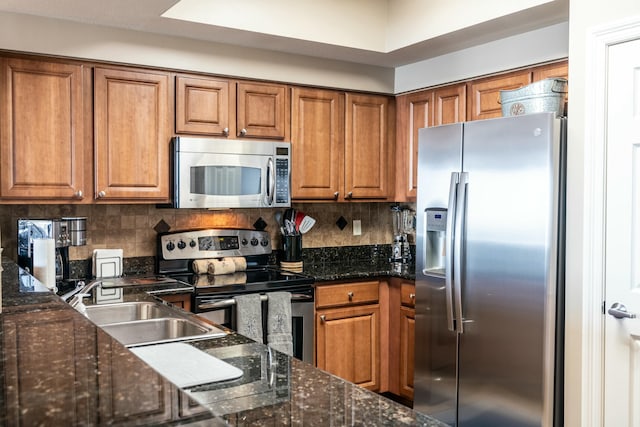 kitchen featuring sink, dark stone countertops, stainless steel appliances, and tasteful backsplash