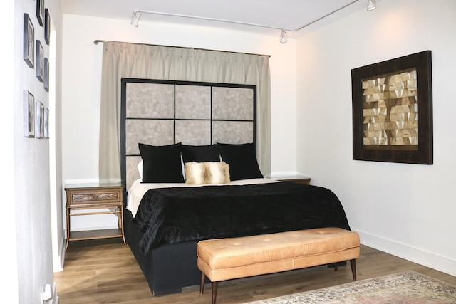 bedroom featuring wood-type flooring and rail lighting