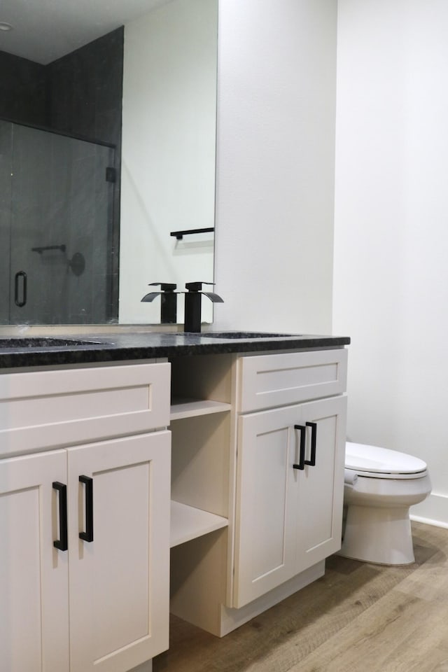 bathroom with hardwood / wood-style floors, vanity, a shower with shower door, and toilet