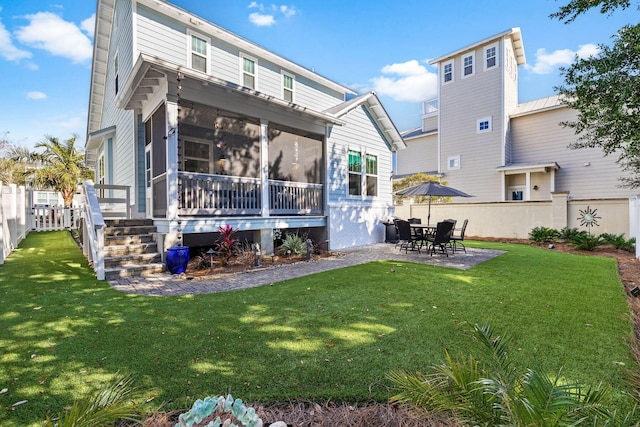 rear view of house featuring a yard, a patio, and a sunroom