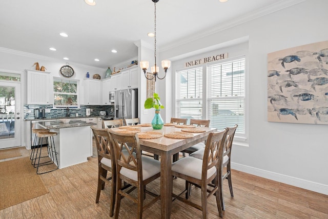 dining area with a chandelier, ornamental molding, and light wood-type flooring