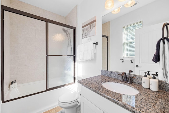 full bathroom featuring combined bath / shower with glass door, vanity, and toilet