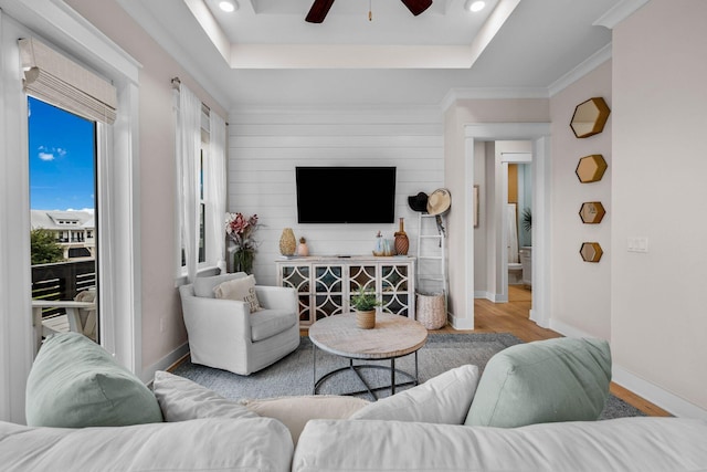 living room with a raised ceiling, ceiling fan, and hardwood / wood-style floors