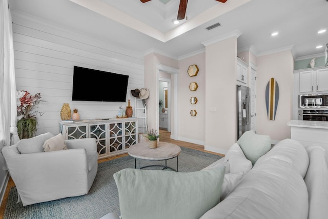 living room with wood-type flooring, ceiling fan, crown molding, and wood walls