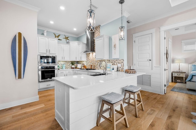 kitchen with white cabinetry, kitchen peninsula, appliances with stainless steel finishes, and wall chimney range hood