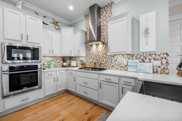 kitchen featuring white cabinets, wall chimney range hood, and appliances with stainless steel finishes