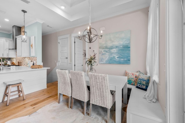 dining room featuring light hardwood / wood-style floors, crown molding, and a chandelier