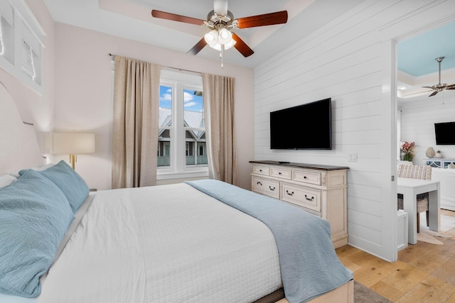 bedroom with ceiling fan, light hardwood / wood-style floors, and a tray ceiling