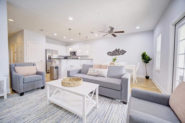 living room with light wood-type flooring and ceiling fan