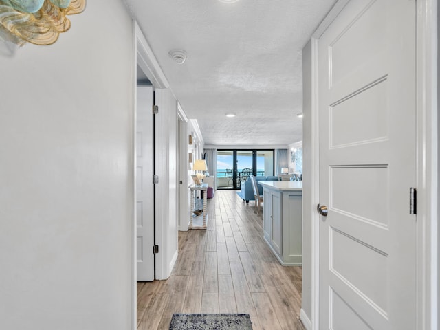 corridor featuring a textured ceiling and light wood finished floors