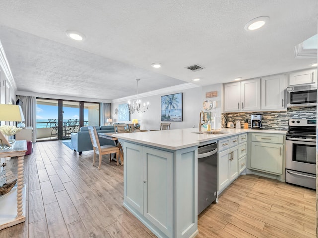 kitchen with visible vents, open floor plan, a peninsula, stainless steel appliances, and a sink